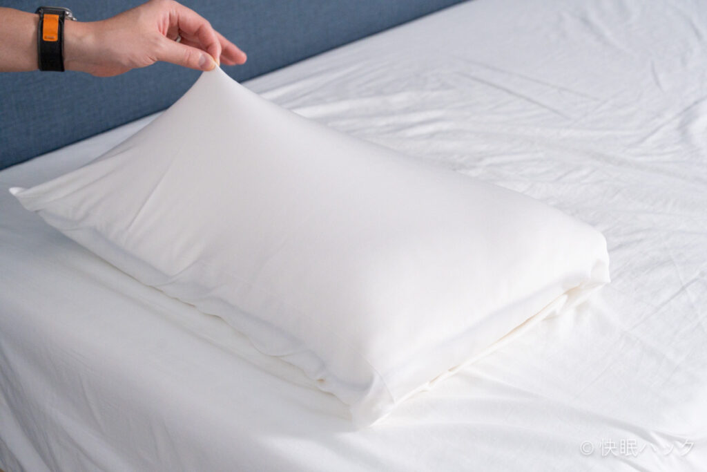 Dr.Bones Pillow（ドクターボーンズピロー）のピローケース（付属枕カバー）の伸縮性をチェックする筆者。非常によく伸びている